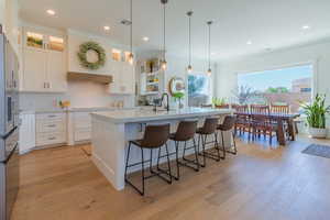 Kitchen with decorative backsplash, stainless steel fridge, white cabinetry, crown molding, and recessed lighting