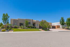 Pueblo revival-style home featuring stucco siding, driveway, and an attached garage