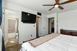 Carpeted bedroom featuring connected bathroom and a ceiling fan