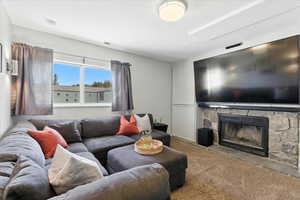 Living room with carpet and a stone fireplace