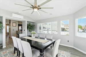 Dining space featuring lofted ceiling, a wall mounted AC, light wood finished floors, and a ceiling fan