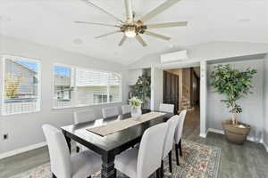 Dining room featuring vaulted ceiling, a ceiling fan, stairway, an AC wall unit, and wood finished floors