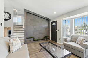 Living room with wood finished floors, stairs, and recessed lighting