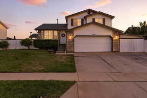 View of front of home featuring stone siding, driveway, and an attached garage