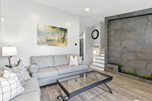 Living room featuring stairs, wood finished floors, vaulted ceiling, and recessed lighting