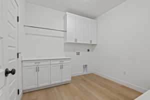 Washroom featuring hookup for an electric dryer, light wood finished floors, cabinet space, and hookup for a washing machine