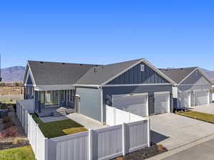 View of front of house featuring a fenced front yard, board and batten siding, driveway, roof with shingles, and a mountain view