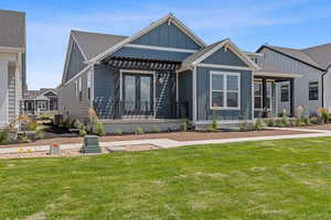 View of front facade featuring board and batten siding, a front lawn, and a shingled roof