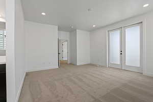 Unfurnished room featuring french doors, light colored carpet, and recessed lighting