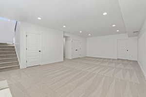Basement featuring stairs, light carpet, and recessed lighting