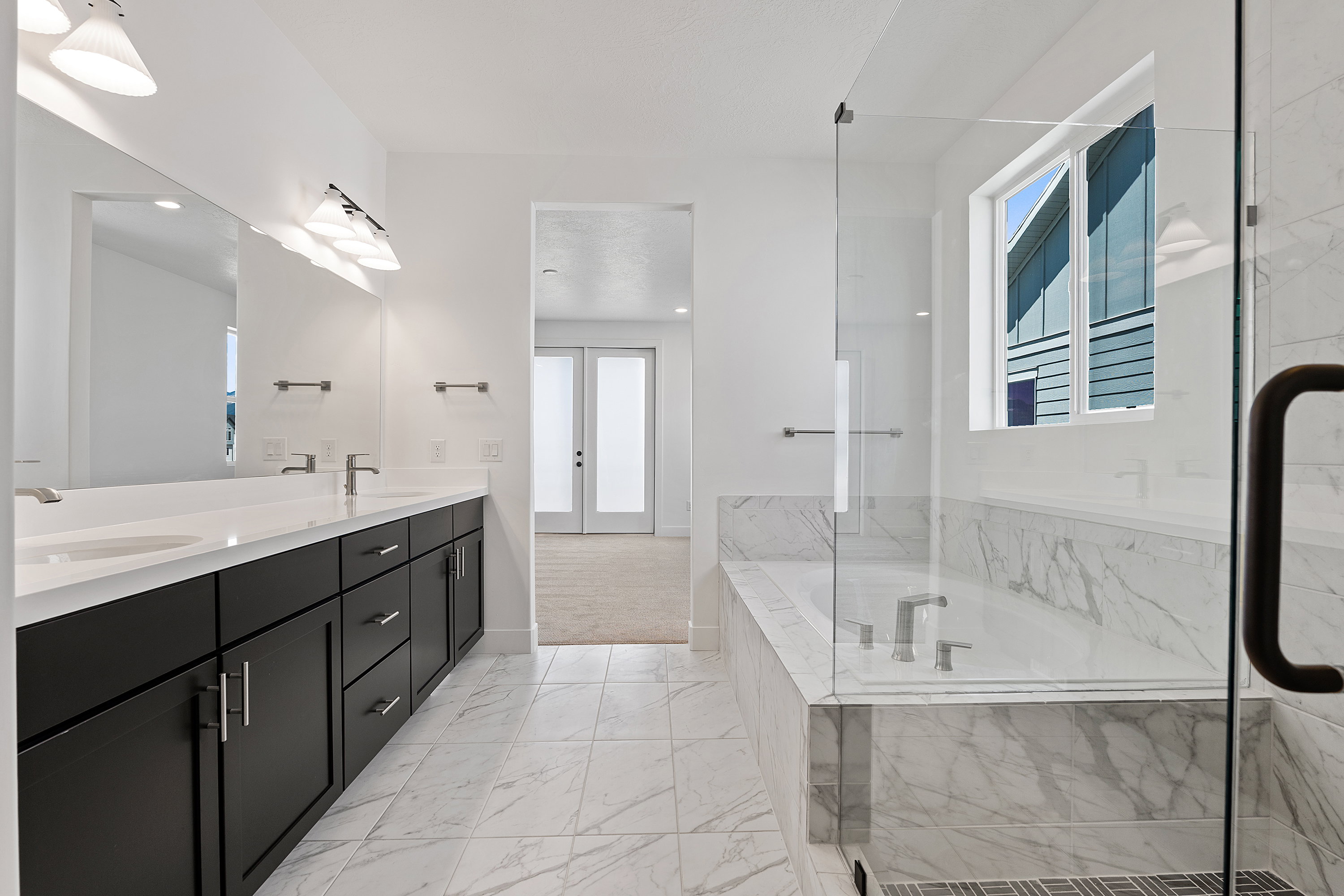 Bathroom featuring french doors, double vanity, a bath, and healthy amount of natural light