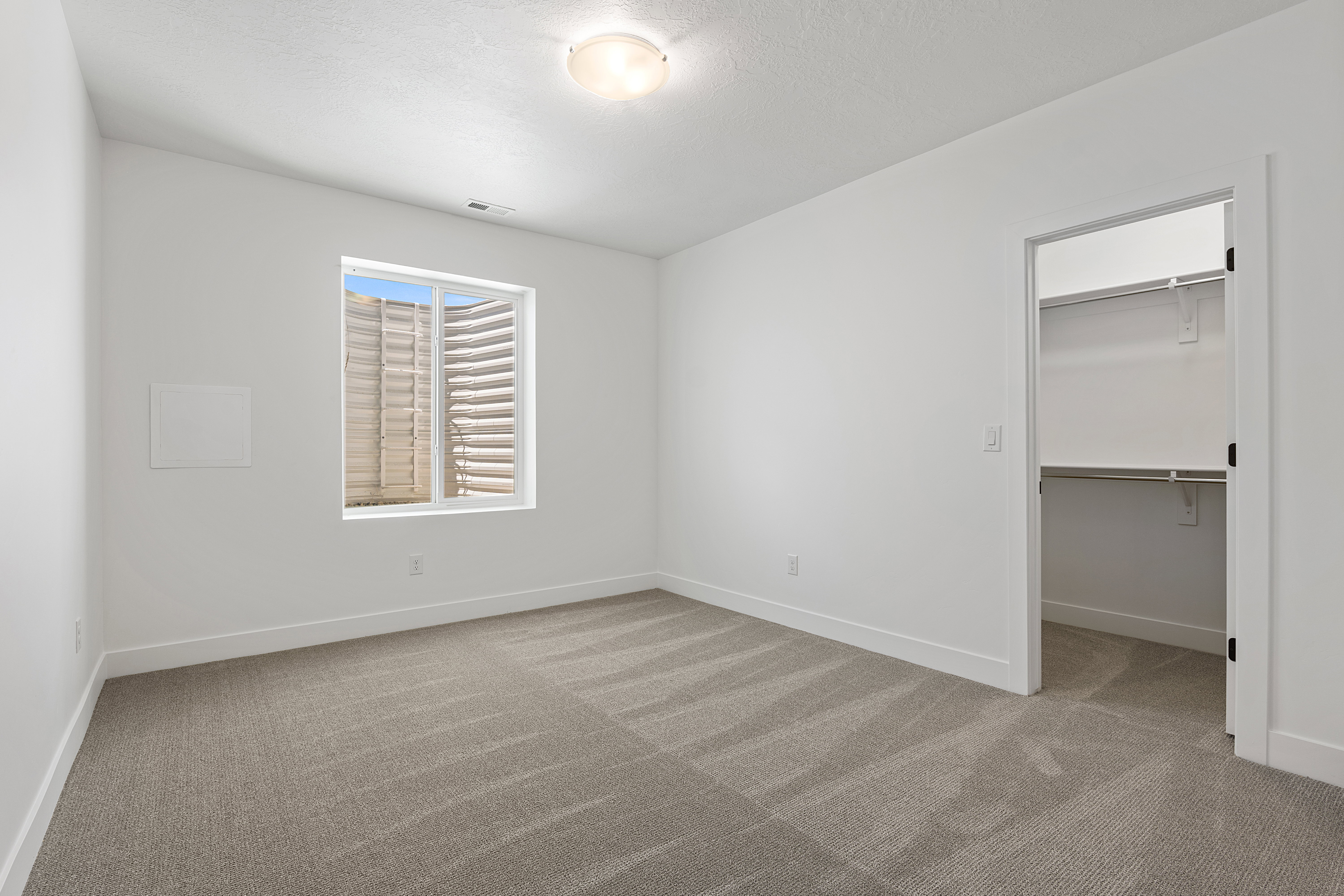 Unfurnished bedroom featuring carpet flooring, a walk in closet, and a textured ceiling