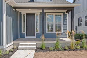 Doorway to property featuring a shingled roof, covered porch, and board and batten siding