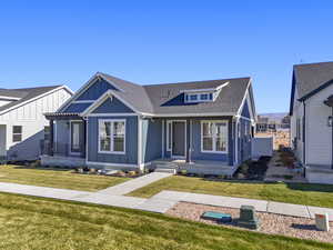 View of front of property with roof with shingles, a front lawn, board and batten siding, and a porch