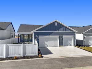 View of front facade with board and batten siding, concrete driveway, a fenced front yard, an attached garage, and a shingled roof