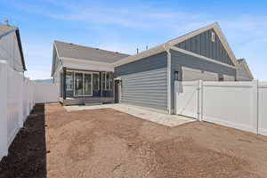 Rear view of property with a gate, a fenced backyard, board and batten siding, roof with shingles, and a sunroom