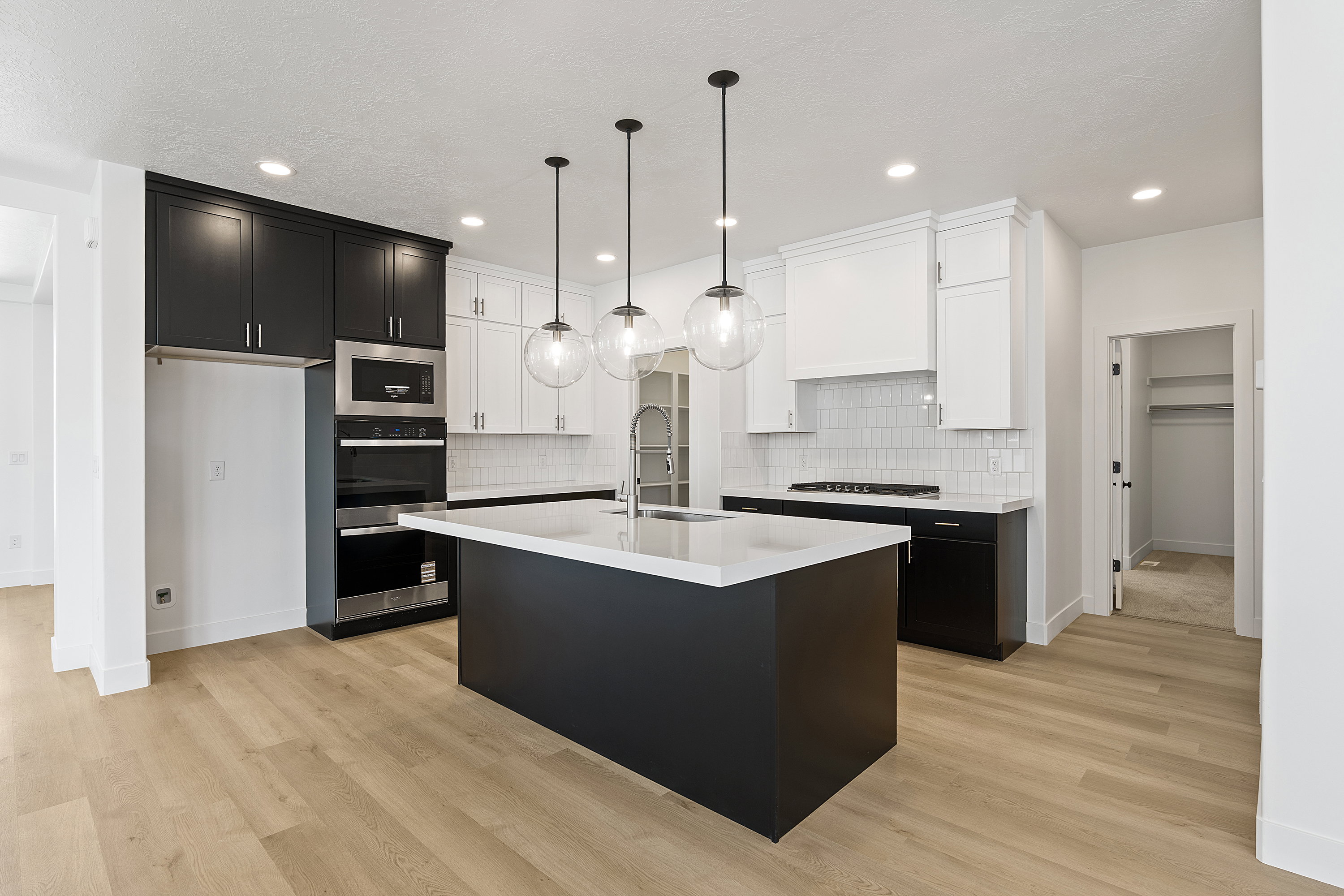 Kitchen featuring light countertops, dark cabinetry, light wood finished floors, a kitchen island with sink, and recessed lighting