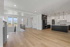 Kitchen with open floor plan, light countertops, tasteful backsplash, light wood-style floors, and recessed lighting