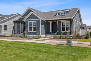 View of front of home with covered porch, board and batten siding, roof with shingles, and a front lawn