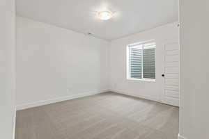 Empty room with light colored carpet and a textured ceiling