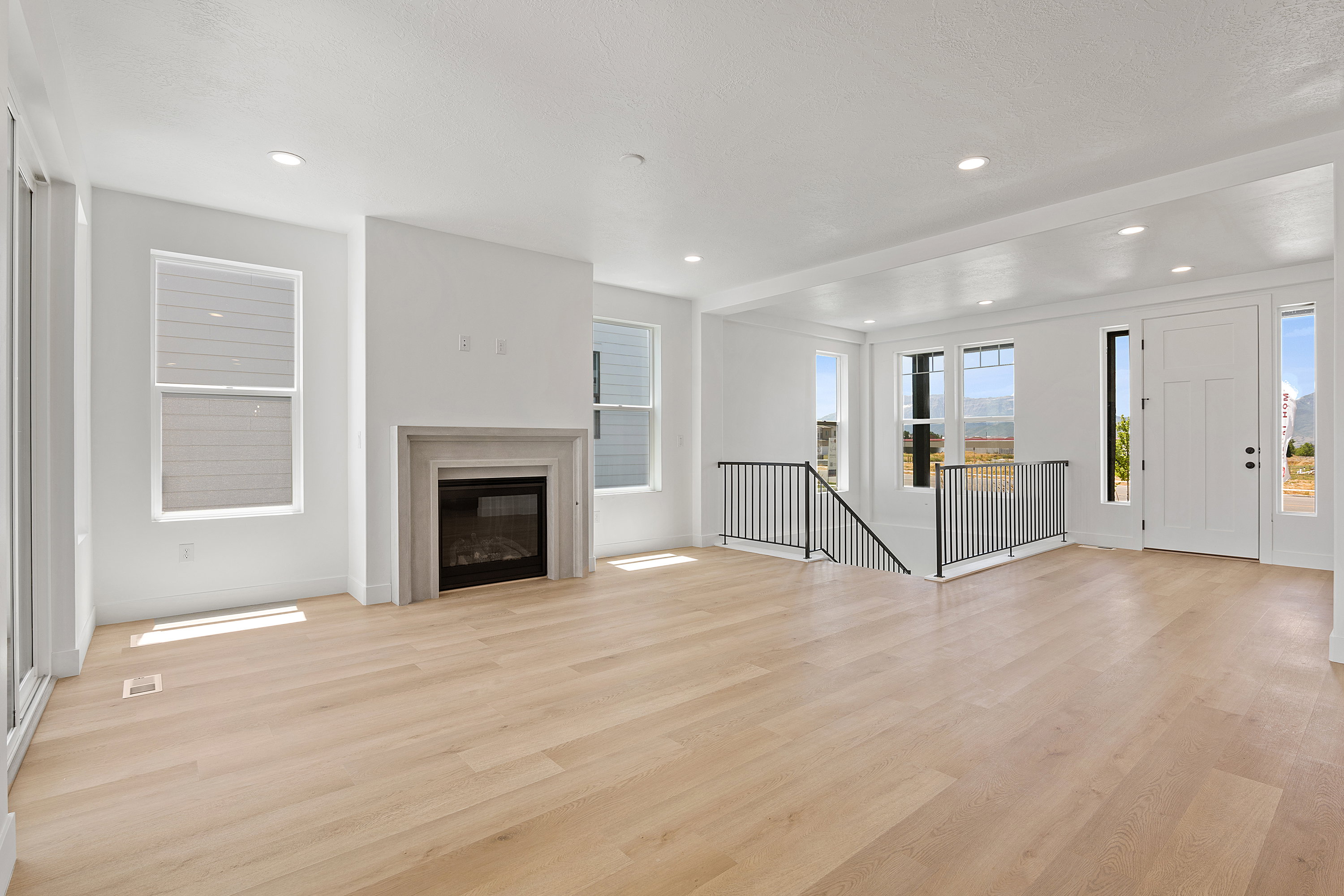 Unfurnished living room with light wood-style flooring, a glass covered fireplace, and recessed lighting