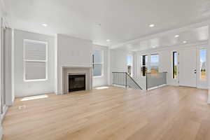 Unfurnished living room with light wood-style flooring, a glass covered fireplace, and recessed lighting