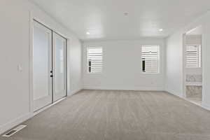 Spare room with light colored carpet, a textured ceiling, and recessed lighting