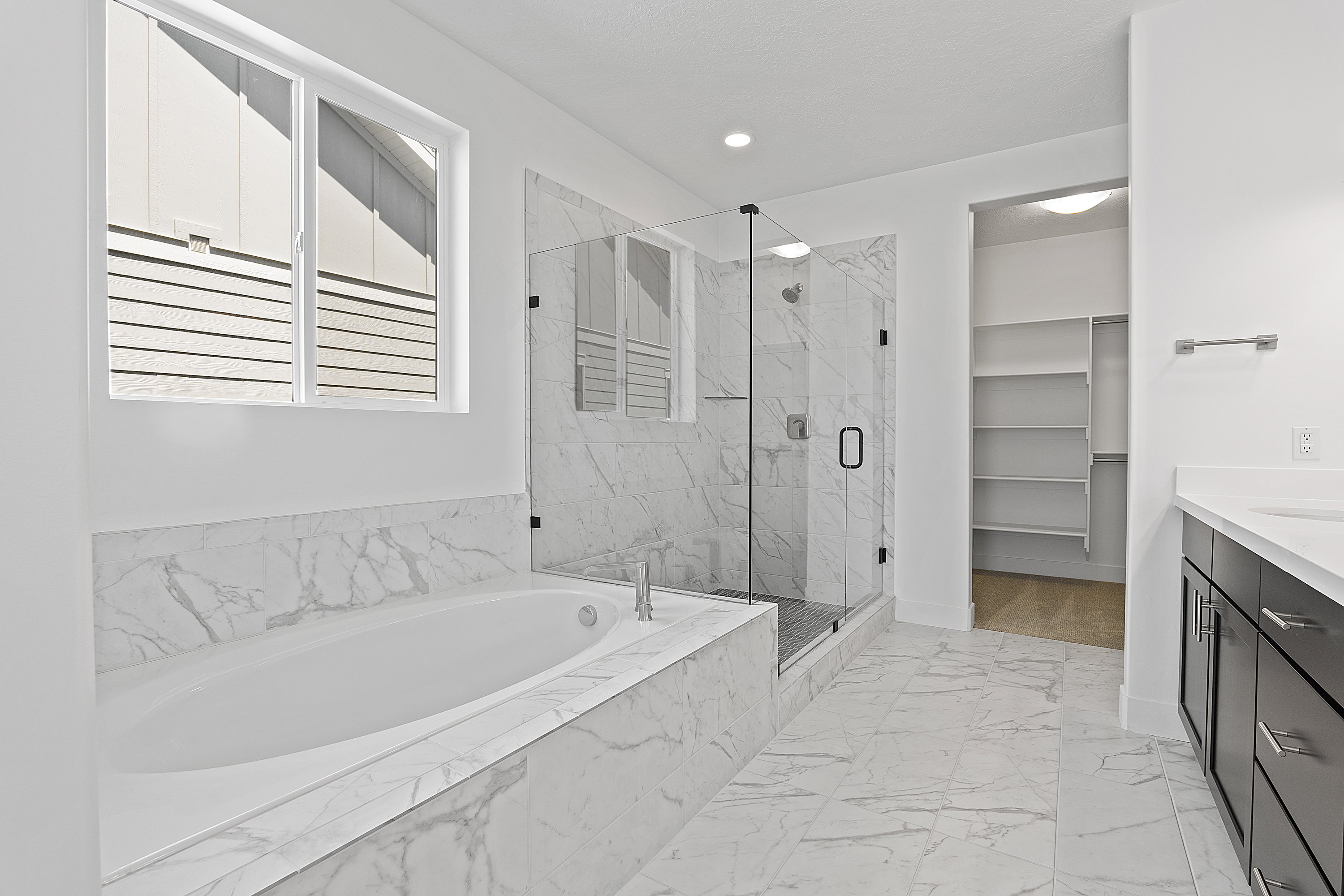 Bathroom with a garden tub, a marble finish shower, marble look tile flooring, vanity, and recessed lighting
