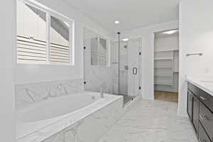 Bathroom with a garden tub, a marble finish shower, marble look tile flooring, vanity, and recessed lighting