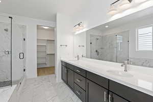 Full bathroom featuring marble finish flooring, a marble finish shower, double vanity, a walk in closet, and recessed lighting