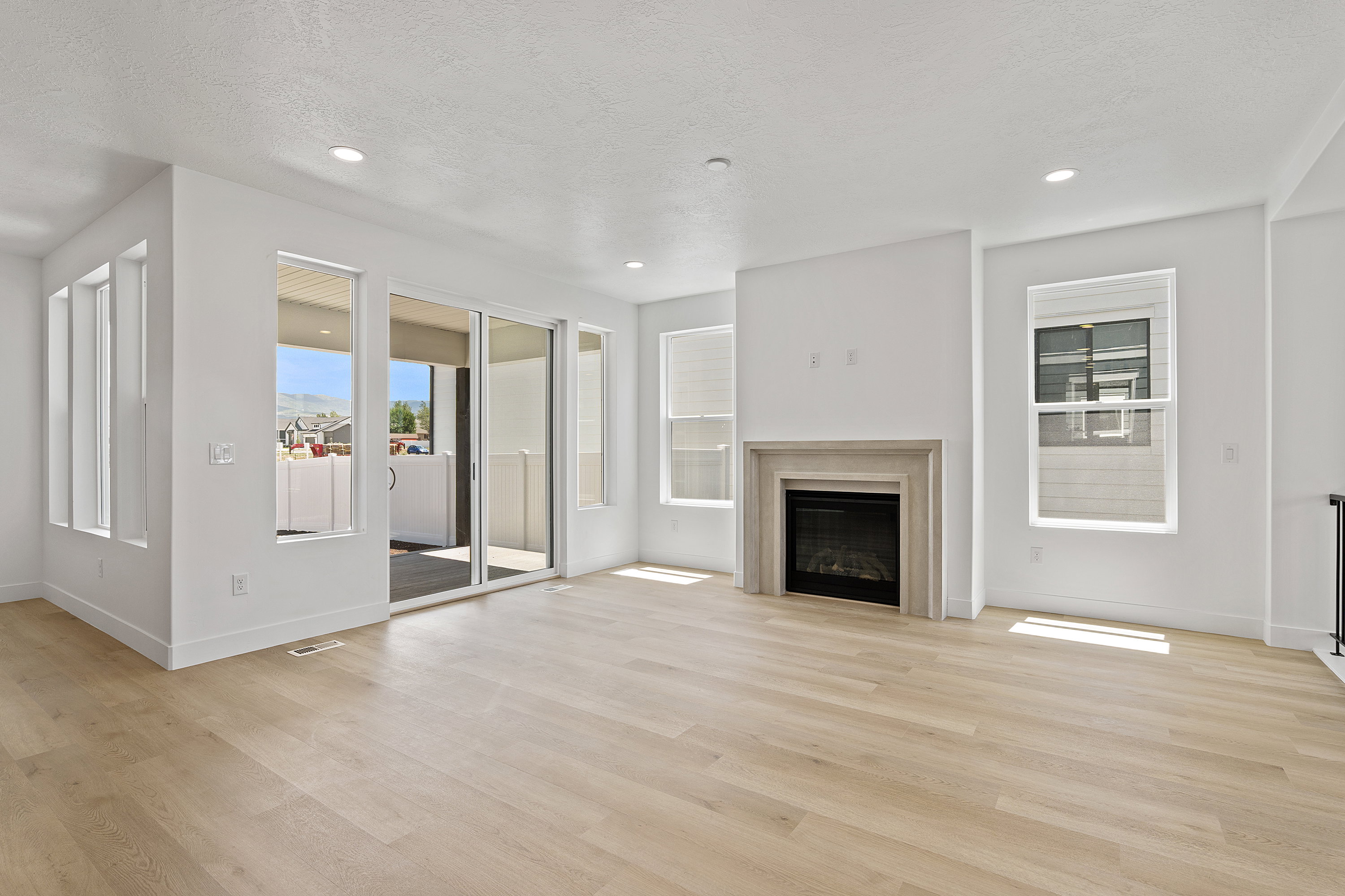 Unfurnished living room featuring light wood-style floors, a fireplace, a textured ceiling, and recessed lighting