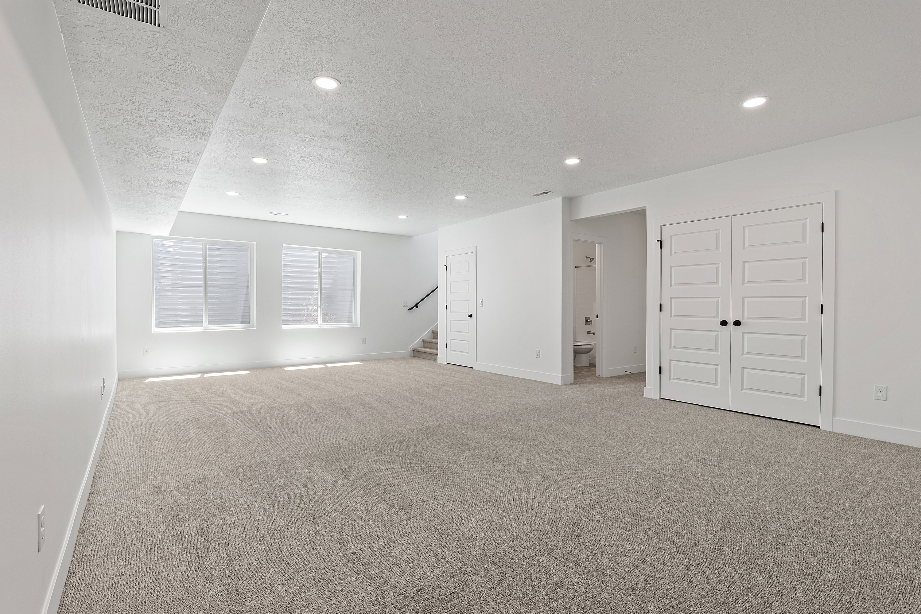 Basement featuring light colored carpet, a textured ceiling, recessed lighting, and stairway