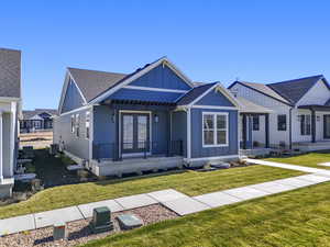 View of front of house with board and batten siding, a shingled roof, a front lawn, and covered porch