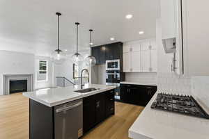 Kitchen with dark cabinets, backsplash, appliances with stainless steel finishes, light countertops, and recessed lighting
