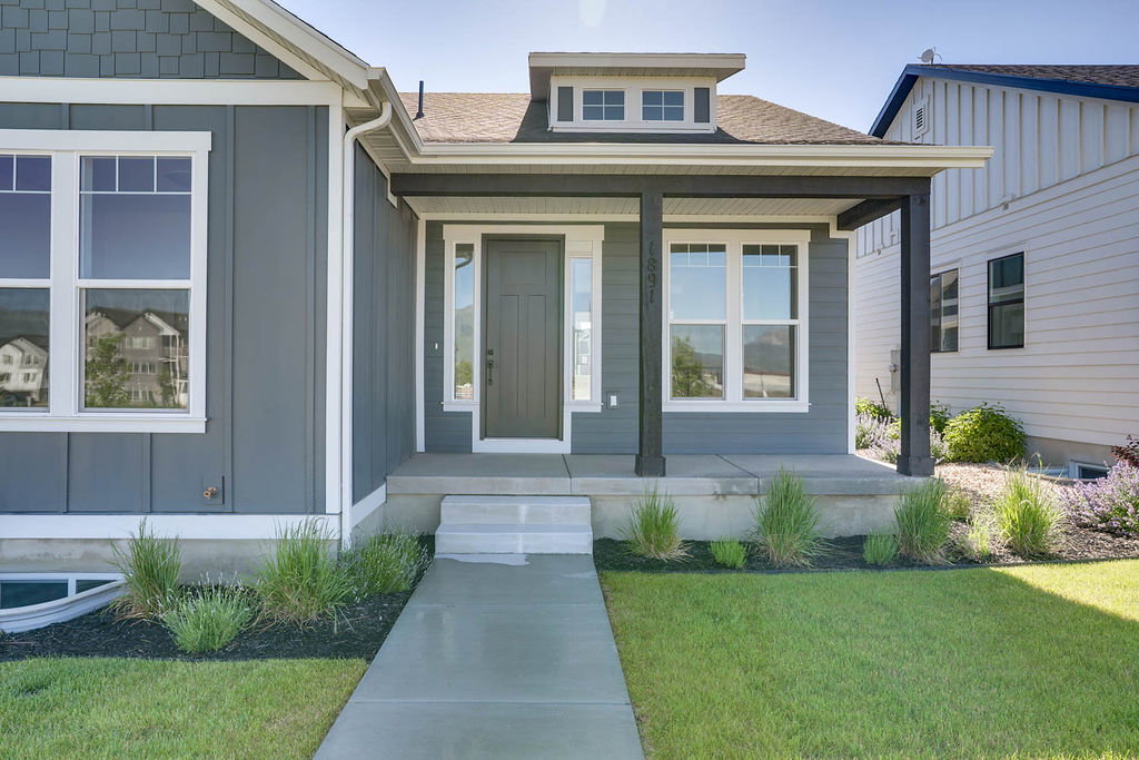 Modern gray siding exterior with white trim and a covered front porch featuring dark structural columns