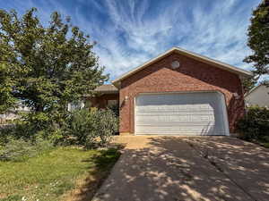 Ranch-style home with an attached garage, concrete driveway, and brick siding