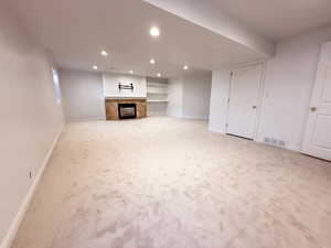 Unfurnished living room featuring recessed lighting, carpet, and a fireplace