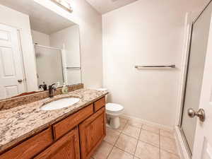 Bathroom featuring tile patterned floors, vanity, and a shower with shower door