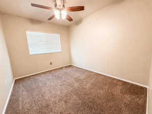Carpeted spare room featuring baseboards and ceiling fan