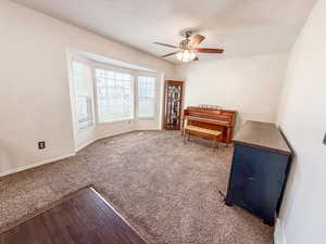 Living area featuring ceiling fan and carpet floors
