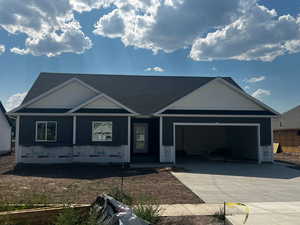 Unfinished property featuring driveway, a garage, and a shingled roof