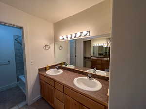 Full bath featuring double vanity, shower / tub combination, and dark tile patterned flooring