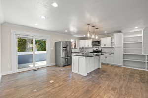 Kitchen with appliances with stainless steel finishes, open shelves, crown molding, plenty of natural light, and white cabinetry