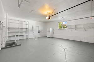 Garage featuring freestanding refrigerator and a garage door opener