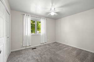 Carpeted empty room featuring baseboards and a ceiling fan