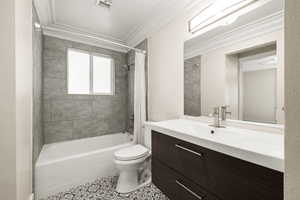 Bathroom with ornamental molding, shower / bath combo, vanity, and tile patterned flooring