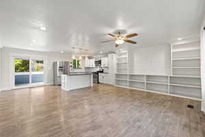 Unfurnished living room featuring light wood finished floors, a ceiling fan, ornamental molding, recessed lighting, and a textured ceiling