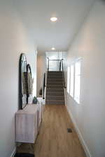 Hallway with stairs and light wood-type flooring