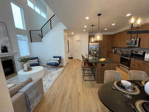 Kitchen featuring brown cabinets, stainless steel appliances, a kitchen breakfast bar, tasteful backsplash, and light wood-style flooring