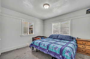 Carpeted bedroom featuring a textured ceiling and baseboards